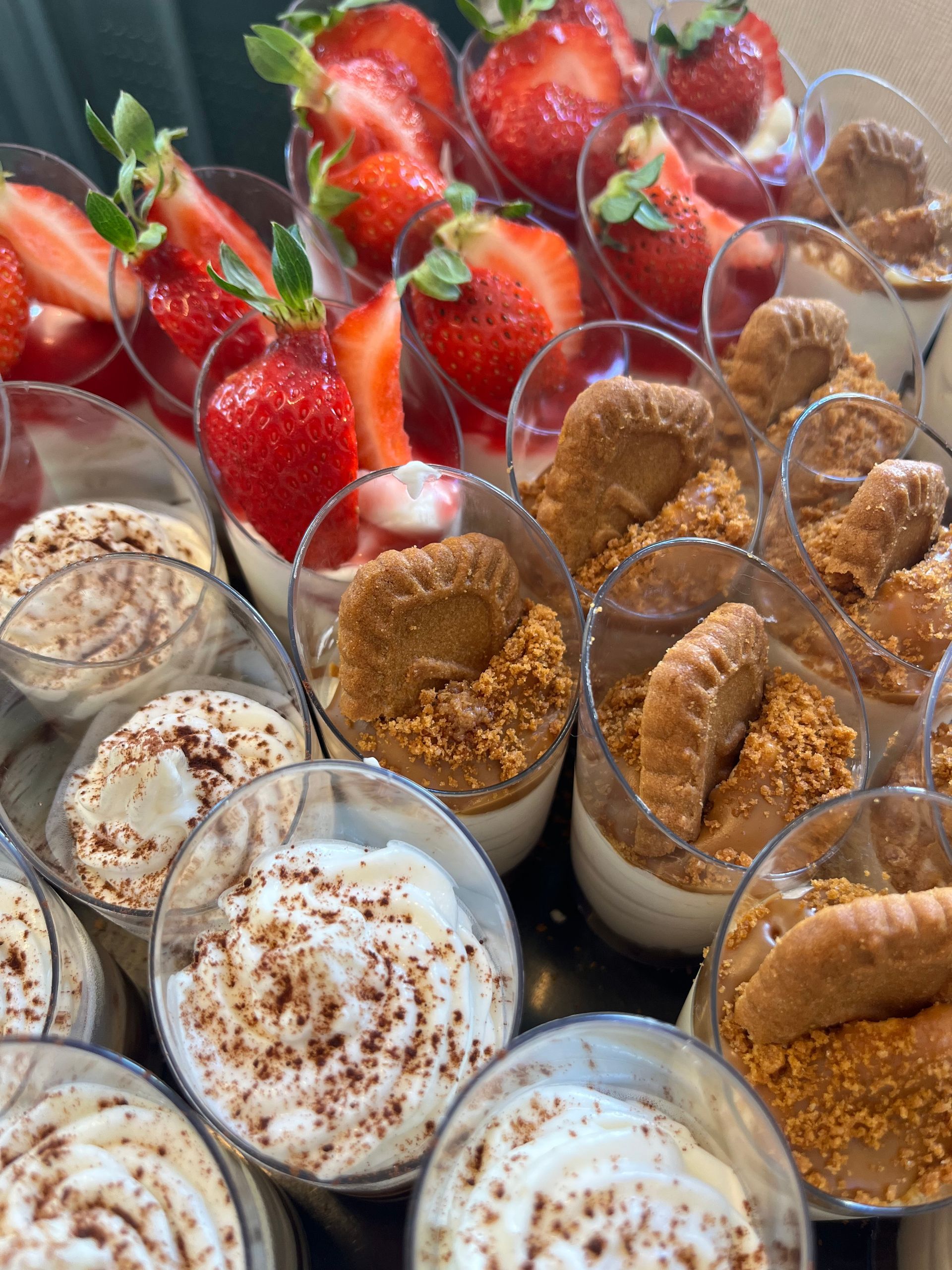 Copas de postre rellenas de fresas, galletas y cremas en capas, dispuestas para servir.