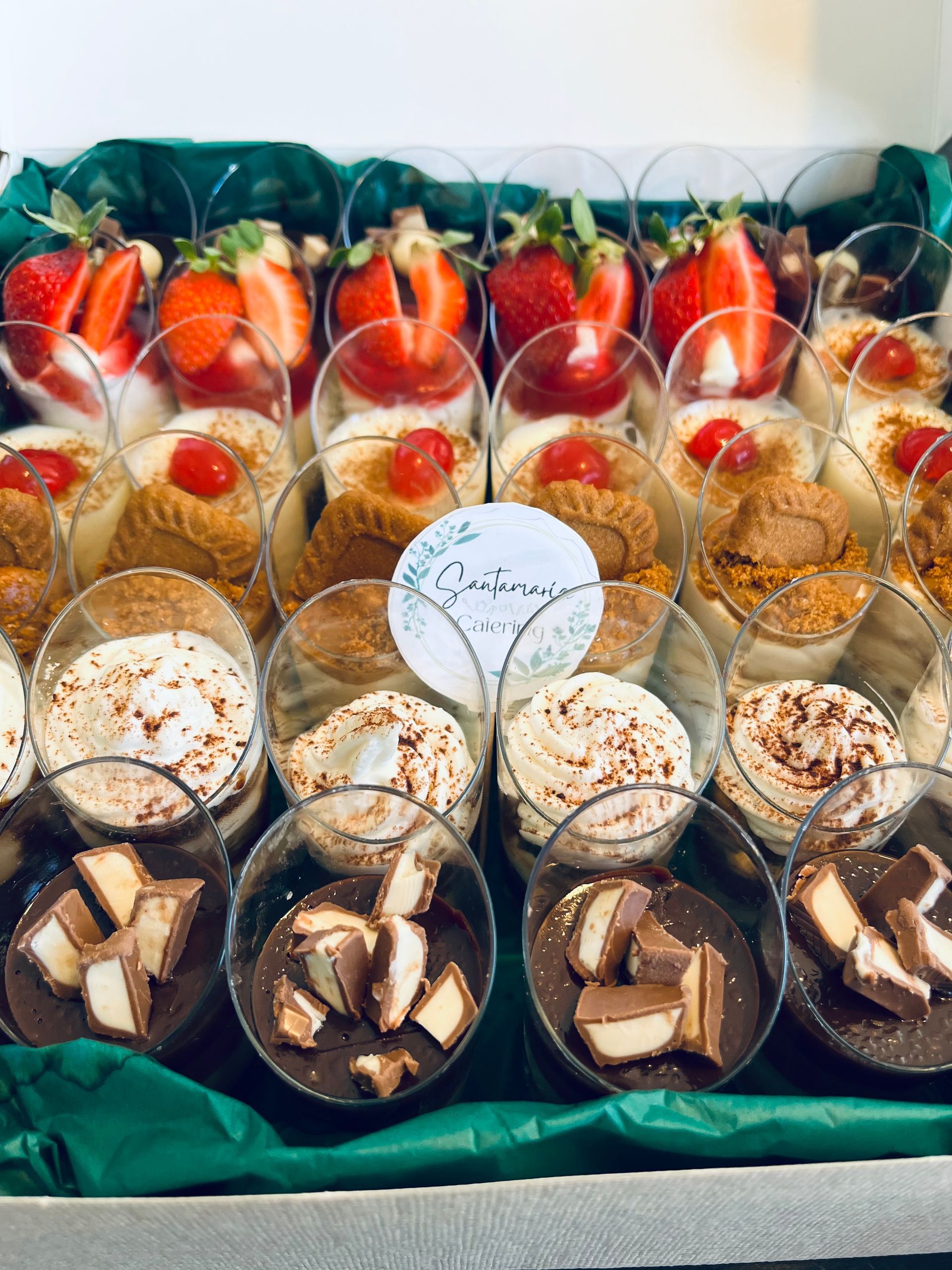 Bandeja de postres con capas de delicias en vasos transparentes: fresas, galletas, mousse y trozos de chocolate.
