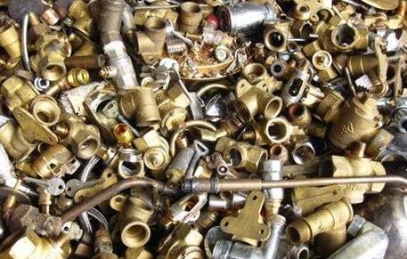 Una pila de tubos y accesorios de latón está sobre una mesa.