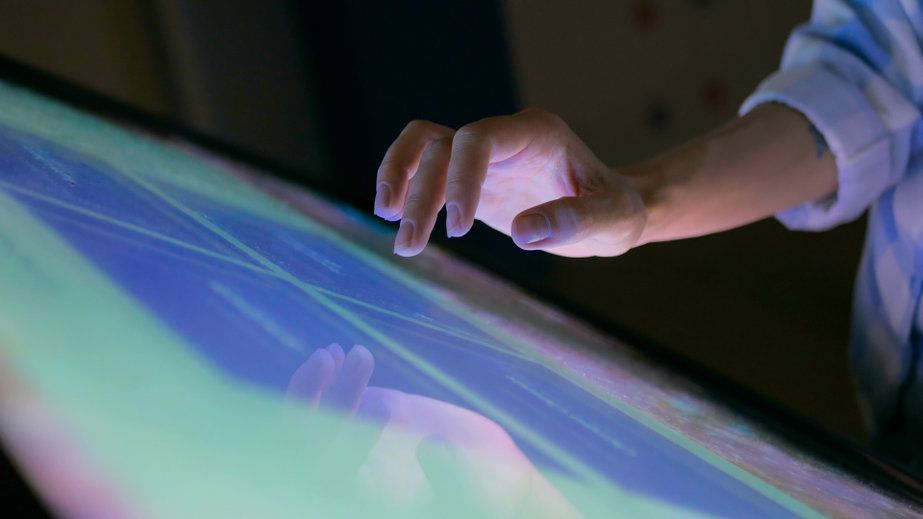 Una persona está tocando una pantalla grande con su dedo.