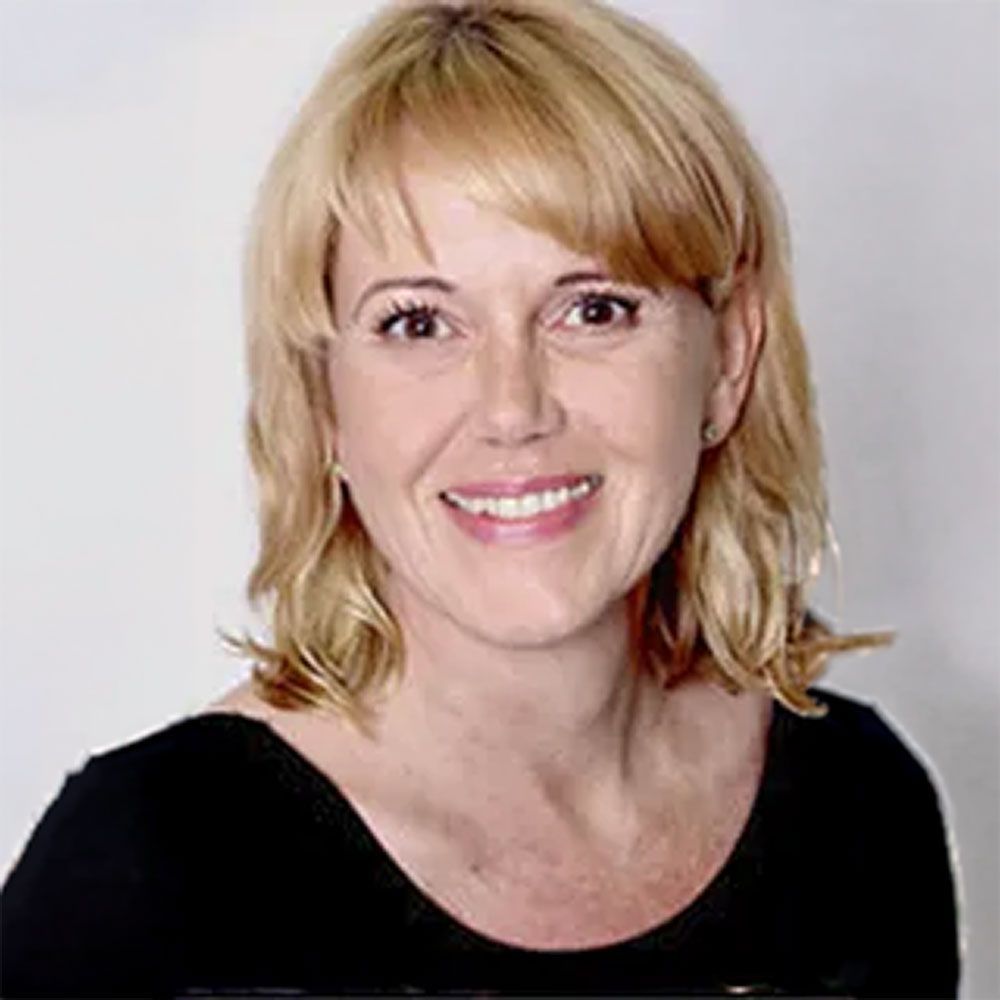 Lächelnde blonde Frau in einem schwarzen Top vor einem einfarbigen hellen Hintergrund