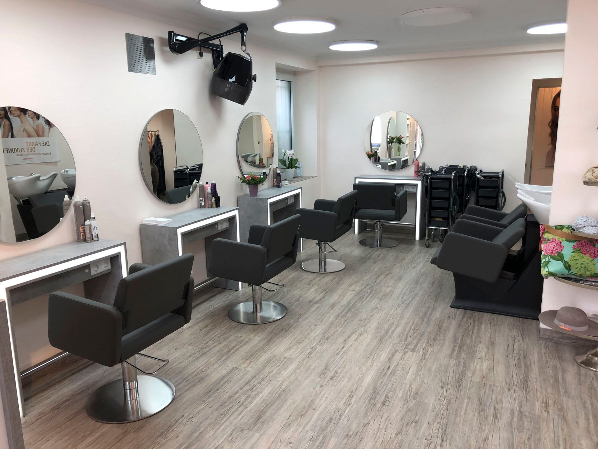 Moderner Friseursalon mit Frisierstühlen, Spiegeln, Waschplätzen und Holzbodenoptik