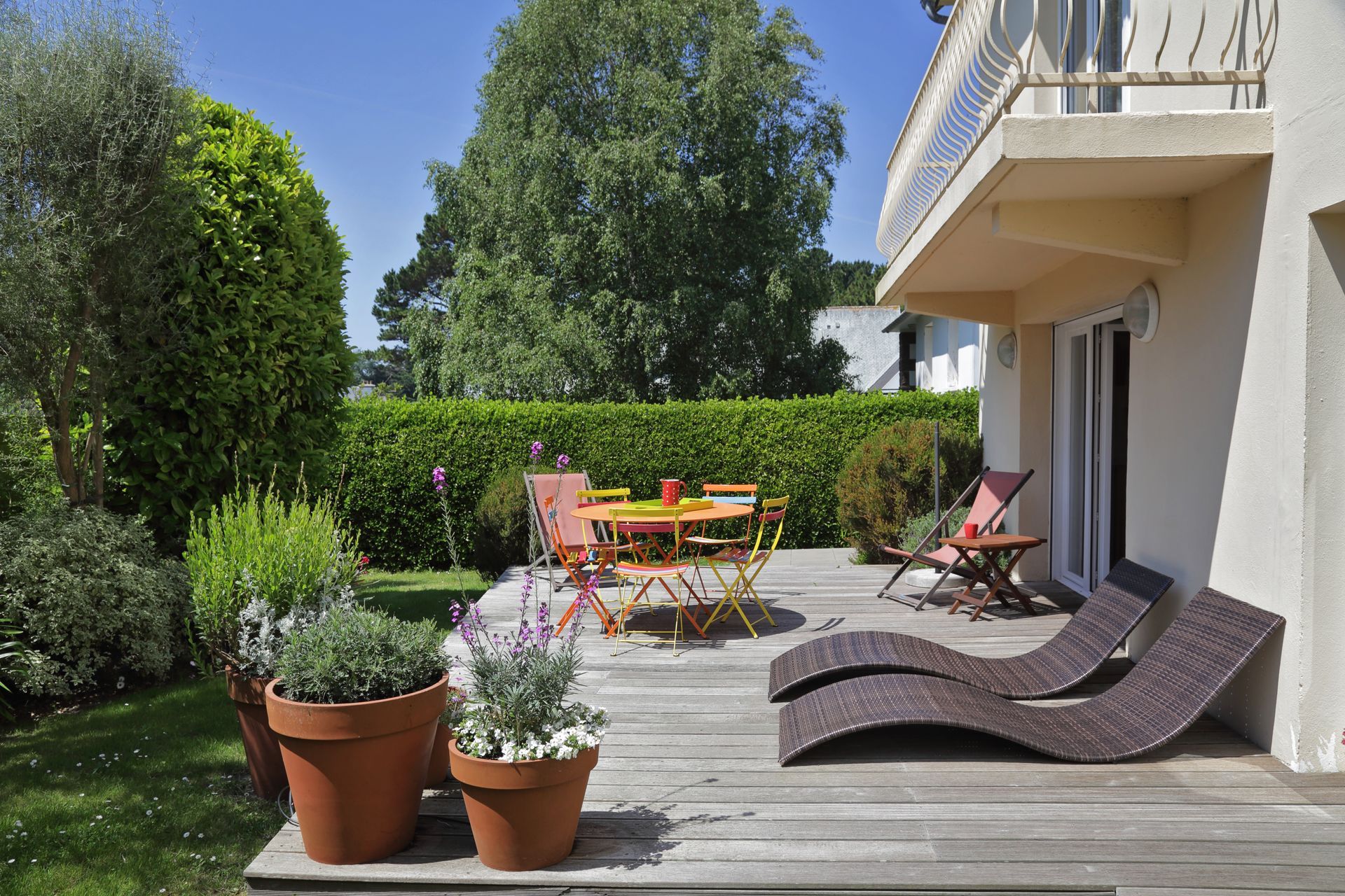 Une terrasse avec une haie en fond