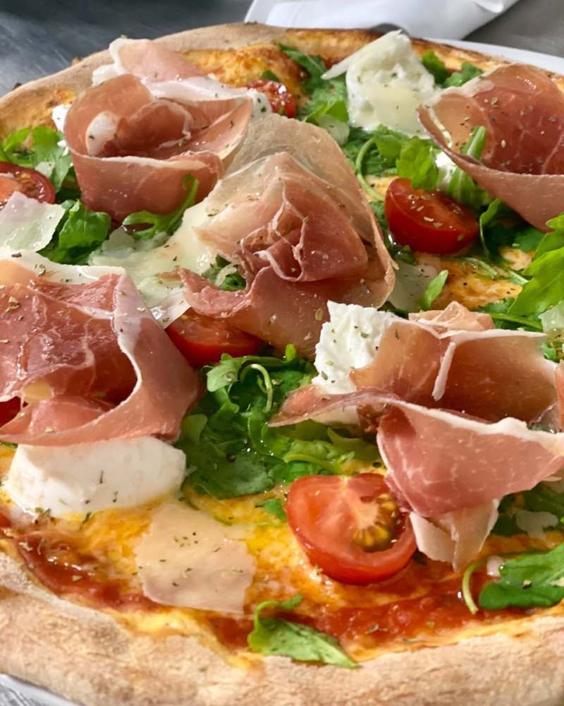 Eine Pizza mit Schinken, Käse, Tomaten und Salat. Foto von Zum Freihof Ristorante Pizzeria