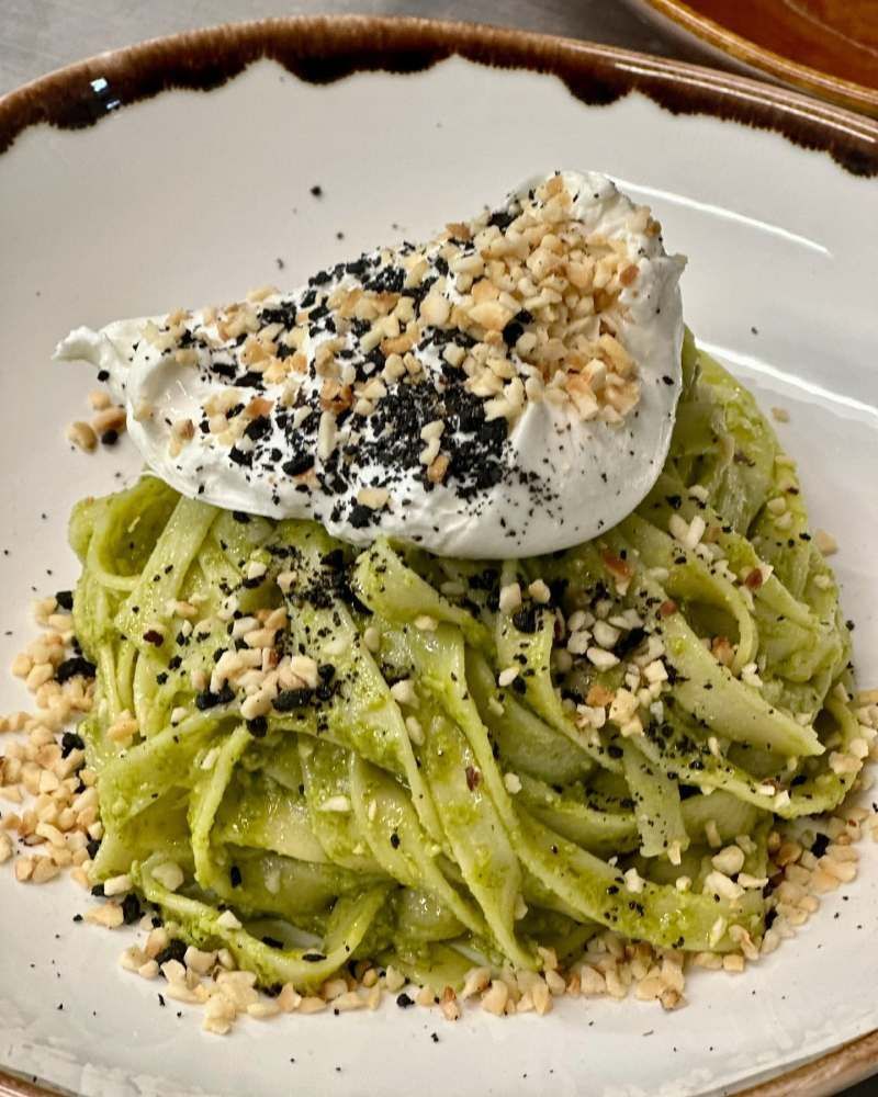 Ein weisser Teller mit grüner Pasta und Sahne. Foto von Zum Freihof Ristorante Pizzeria