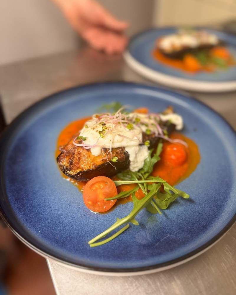 Ein blauer Teller mit einem Stück Fleisch und Gemüse. Foto von Zum Freihof Ristorante Pizzeria