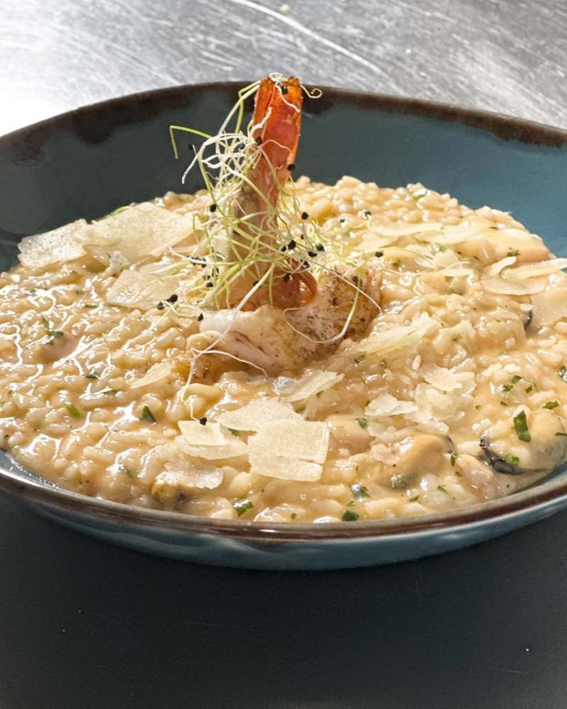Eine Nahaufnahme einer Schüssel Risotto mit Garnelen obendrauf.