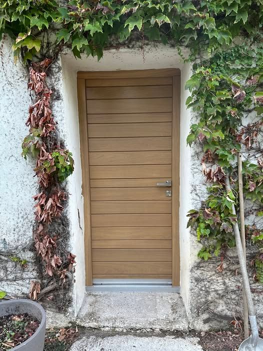 Porte en bois et façade en pierre blanche avec lierre grimpant.