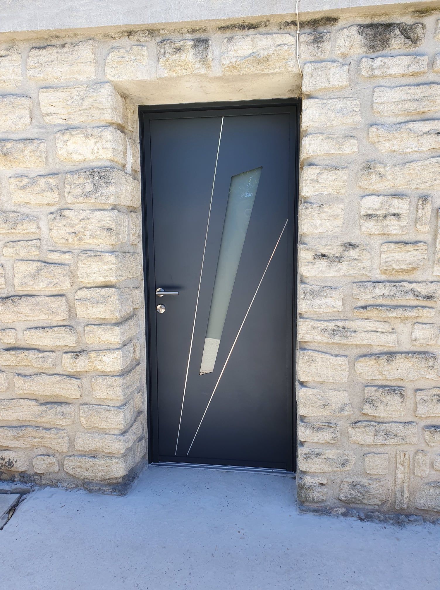 Mur en pierre avec une porte d'entrée avec vitrage géométrique et décorations.