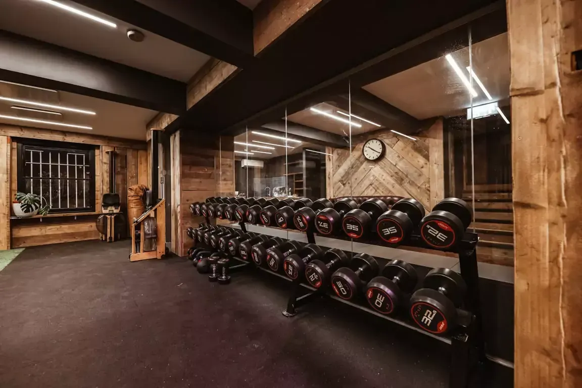 A gym with a lot of dumbbells and a clock on the wall.