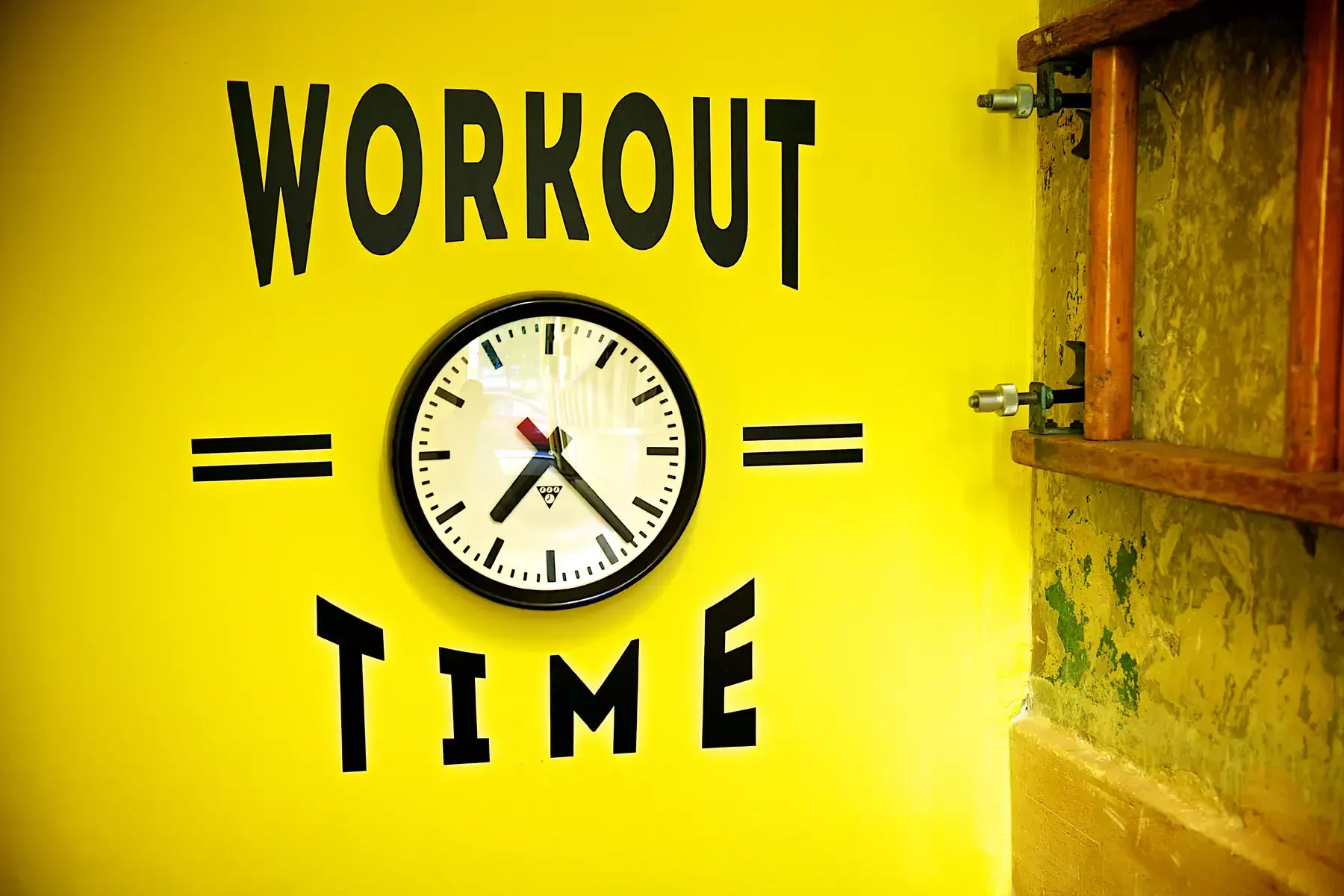 A clock on a yellow wall that says workout time at Terra Hale, London