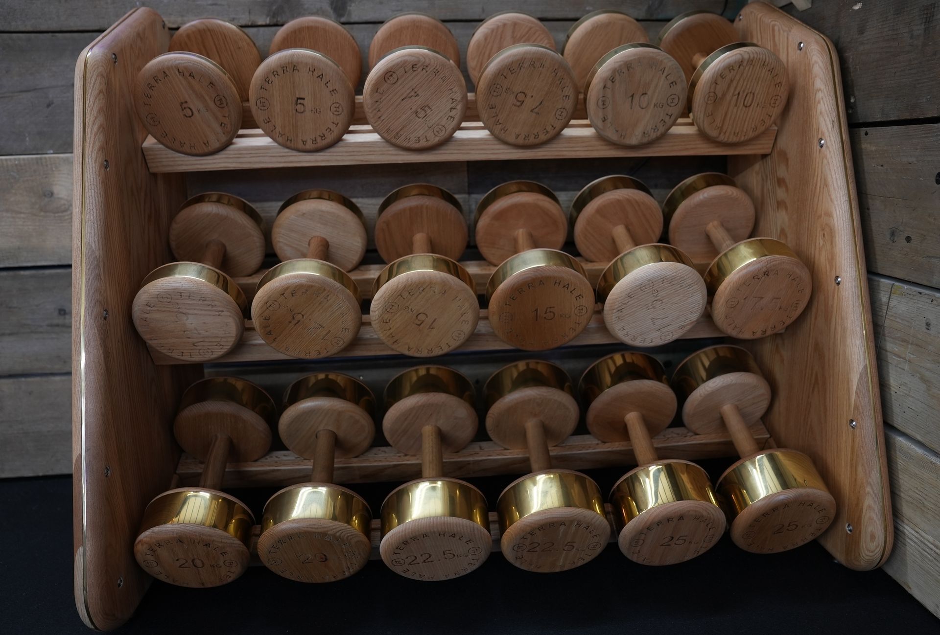 A wooden rack with gold dumbbells on it