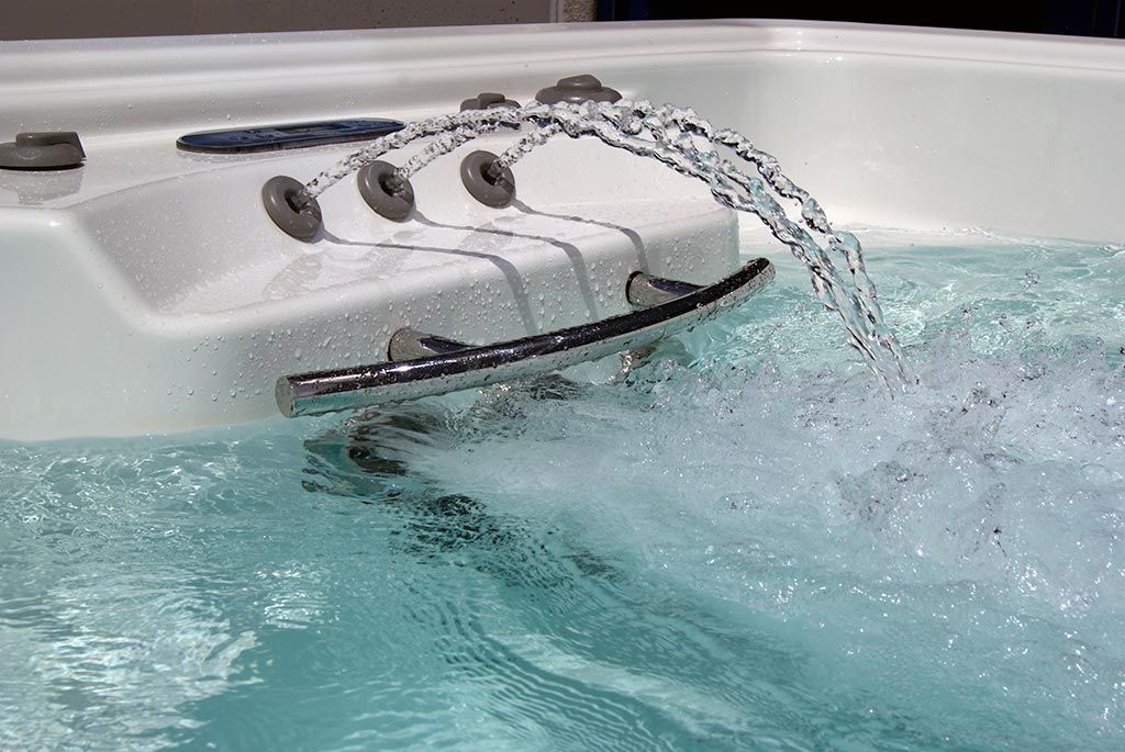 Bañera de hidromasaje con chorros de agua que salpican el agua burbujeante, junto al borde de la bañera.