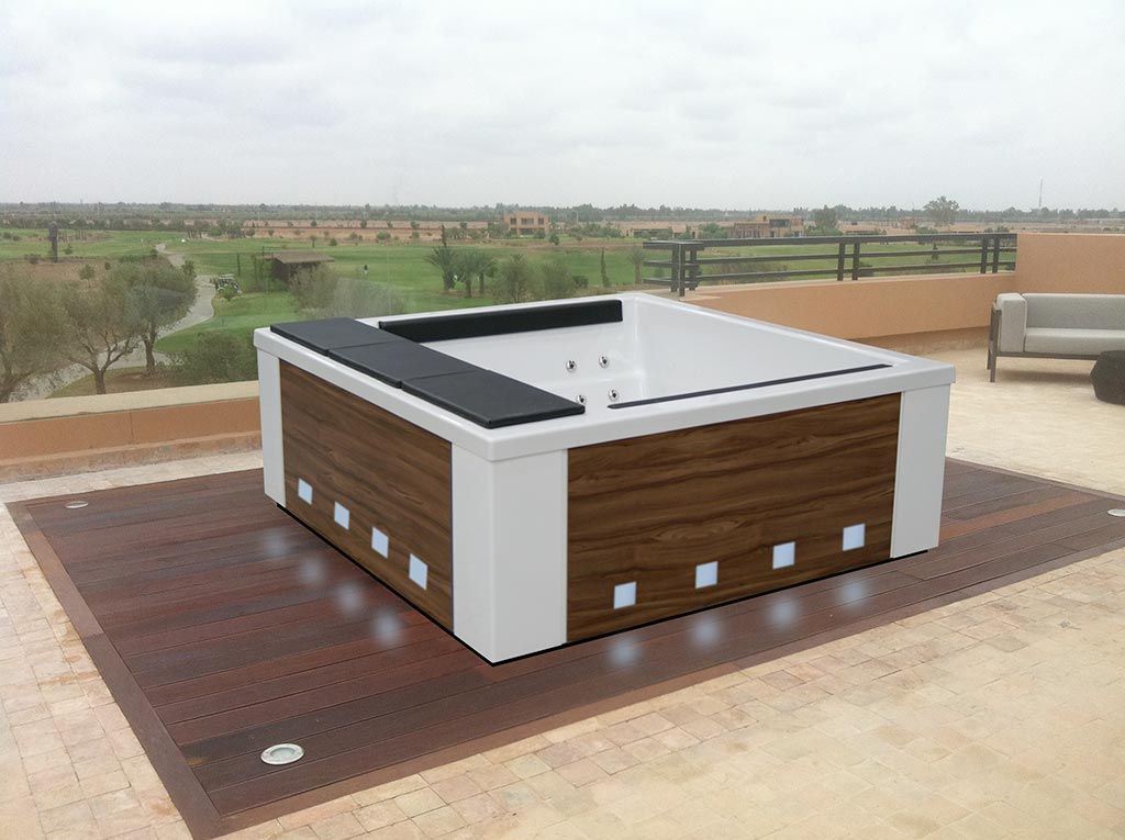 Jacuzzi en un patio en la azotea con exterior marrón y blanco, con vista a un campo de golf.