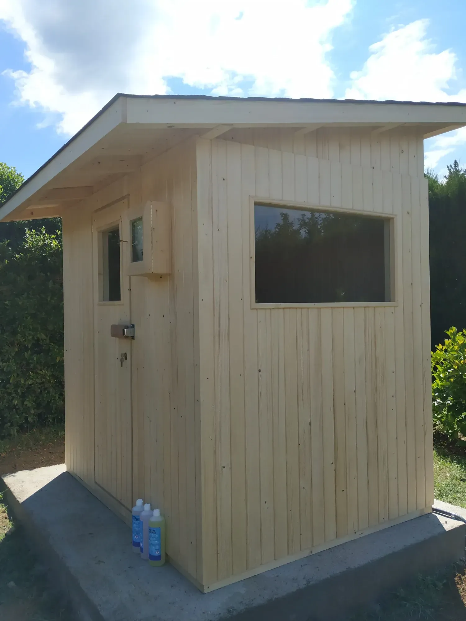 Sauna de madera junto a una piscina en una terraza de madera.