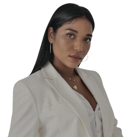 Femme aux cheveux noirs, portant un blazer blanc, regardant la caméra.