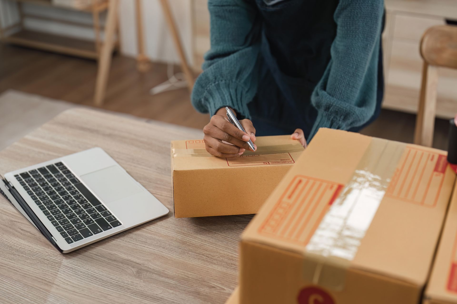 Kartons, Laptop, Person schreibt auf Karton