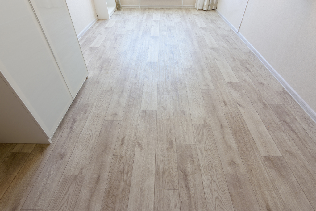 Parquet clair dans une pièce aux murs blancs et une armoire à gauche.