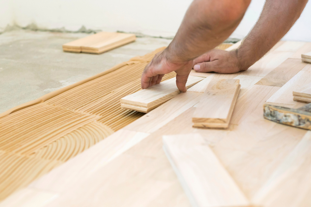 Personne installant des lames de parquet avec de la colle.