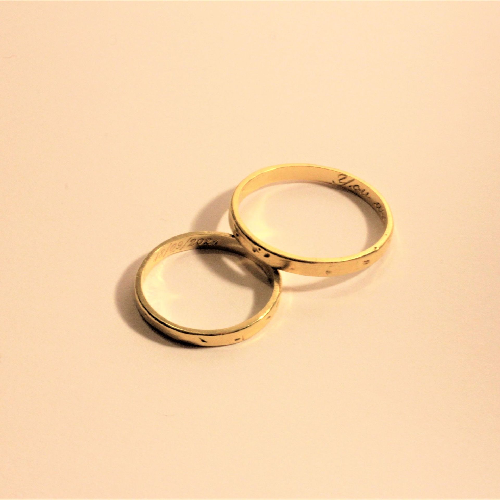 Un par de anillos de boda de oro sobre una superficie blanca.