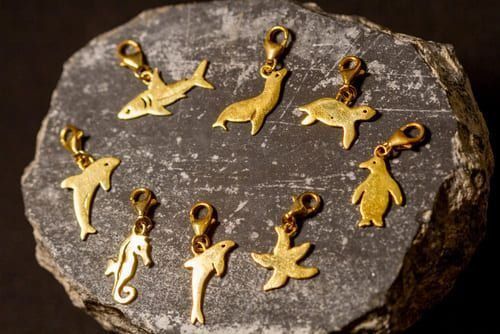 Un grupo de colgantes de oro con forma de delfines y pingüinos están sentados encima de una roca.