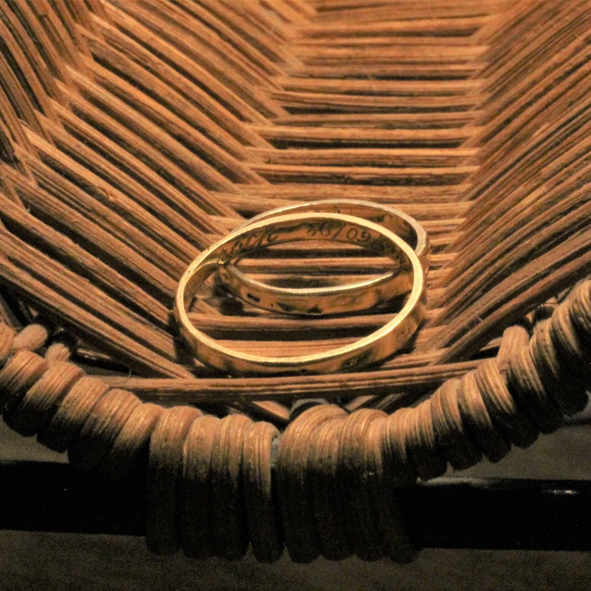 Un par de anillos de boda de oro en una cesta de mimbre.