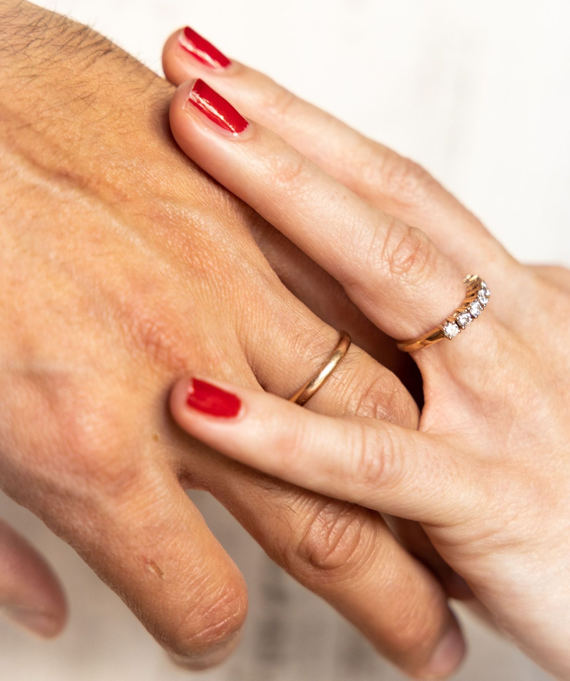 Un hombre y una mujer tomados de la mano con anillos en los dedos.