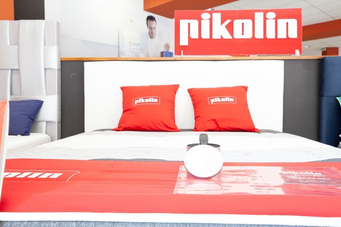 Un llit amb coixins vermells i un rètol que diu Pikolin
