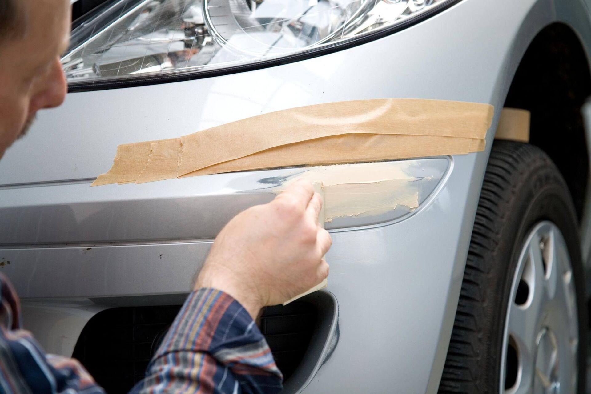 Trio Automobiltechnik GmbH Person lackiert die Frontschürze eines Autos