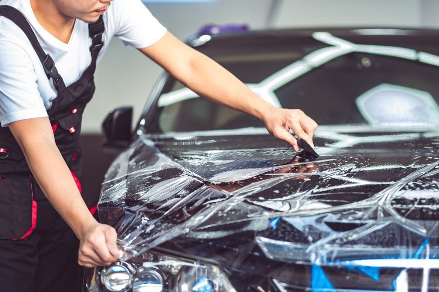Un technicien fixe un sticker sur une voiture noire