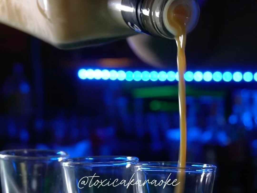Se vierte una botella de alcohol en un vaso de chupito.