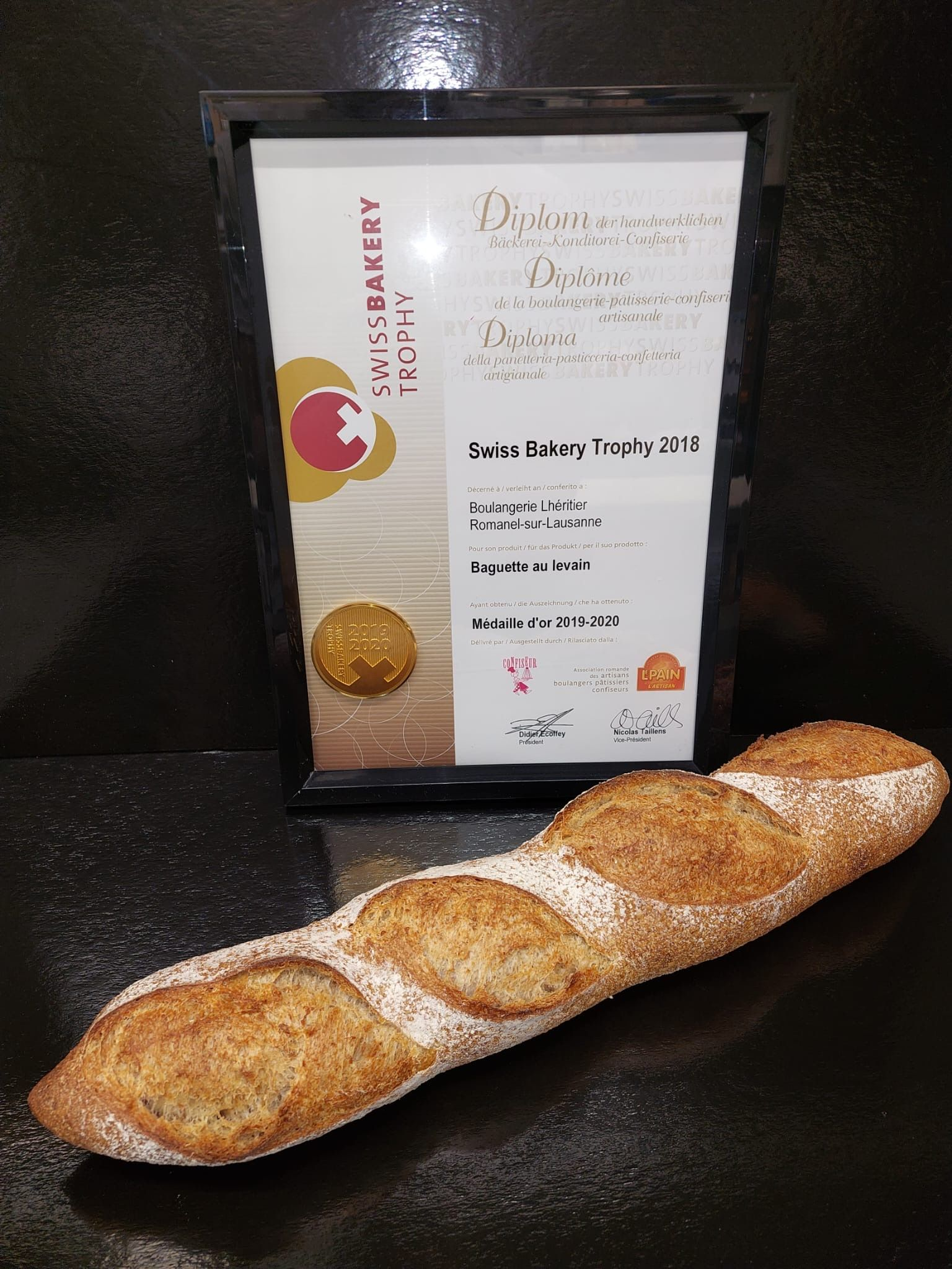 Longue baguette devant une récompense encadrée.