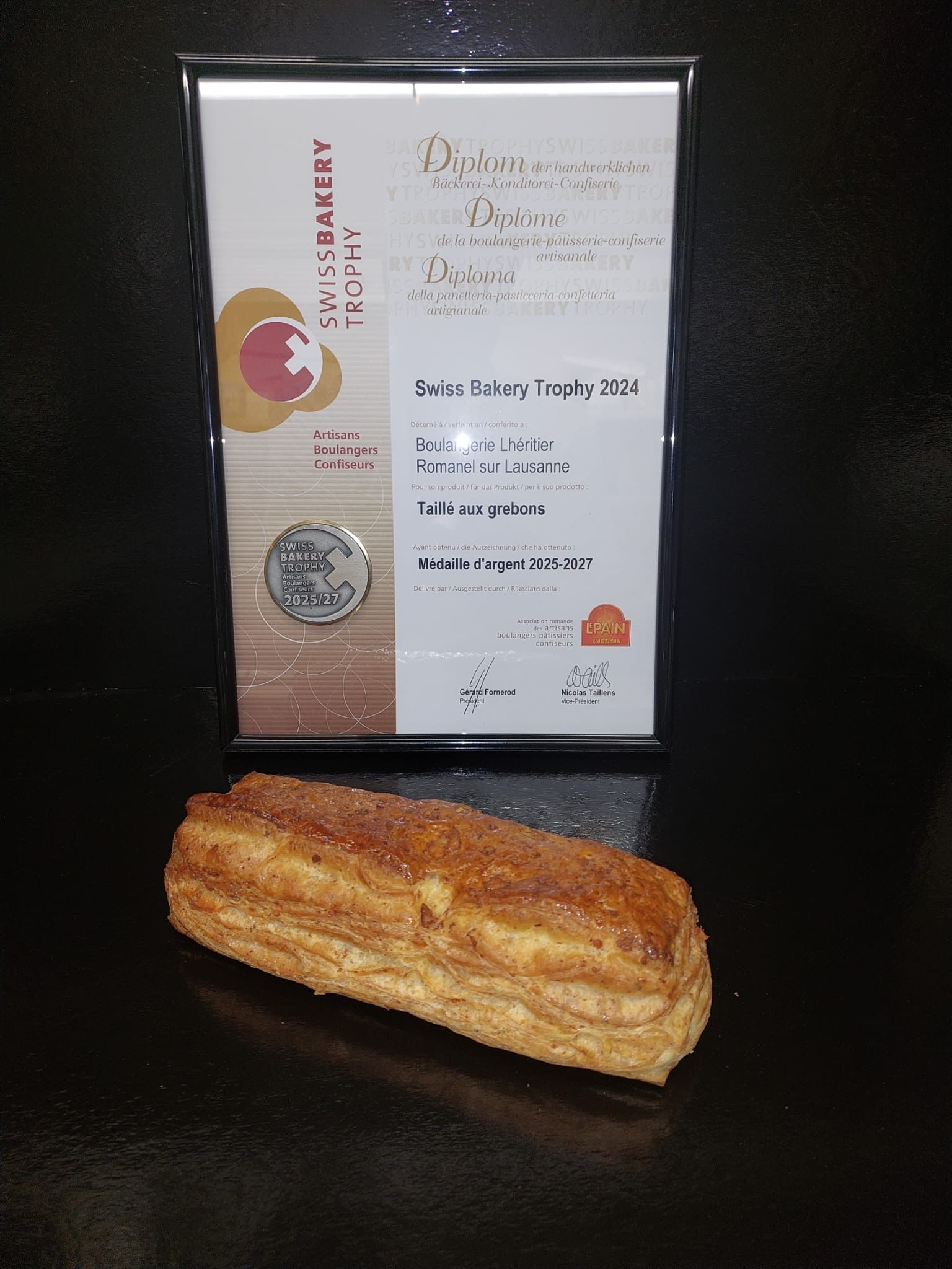 Pâtisserie au sucre et à la cannelle devant un certificat encadré, probablement pour une boulangerie.