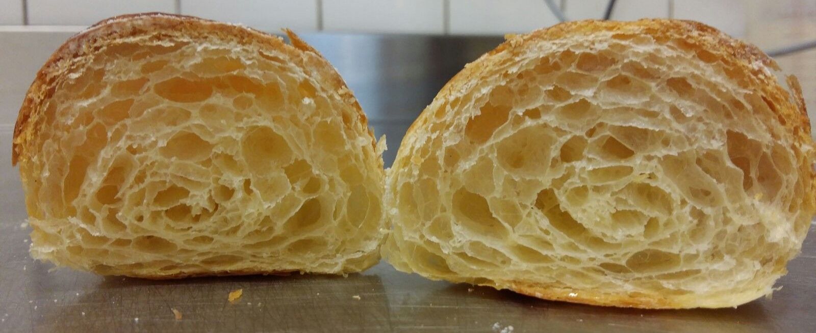 Deux moitiés d'un croissant, montrant des couches de pâte aérée et une croûte dorée.