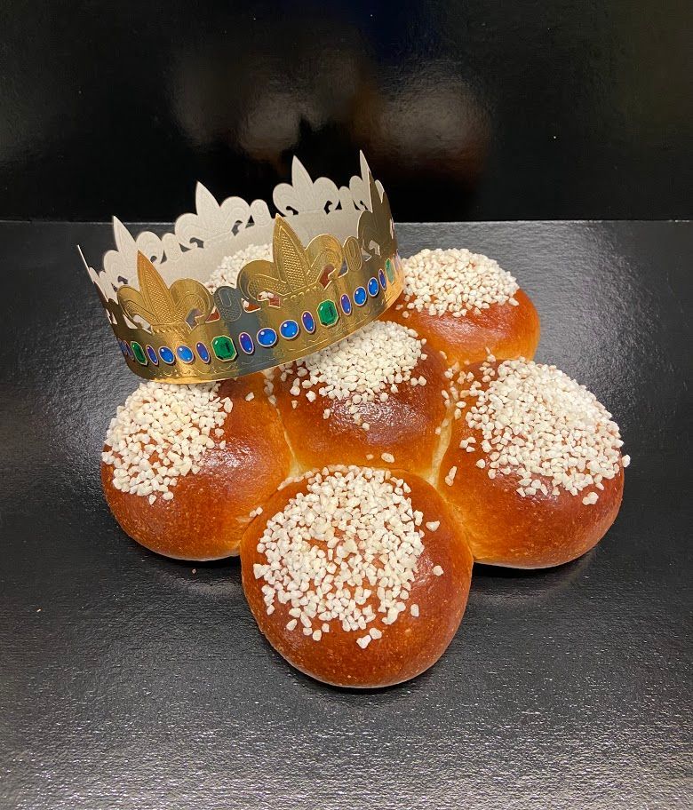 Vitrine de boulangerie : étagères de pains, viennoiseries et pains variés ; éclairage chaleureux, présentoirs en bois.