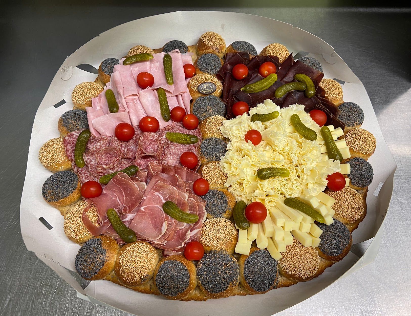Plateau circulaire avec diverses viandes, fromages, cornichons et tomates.