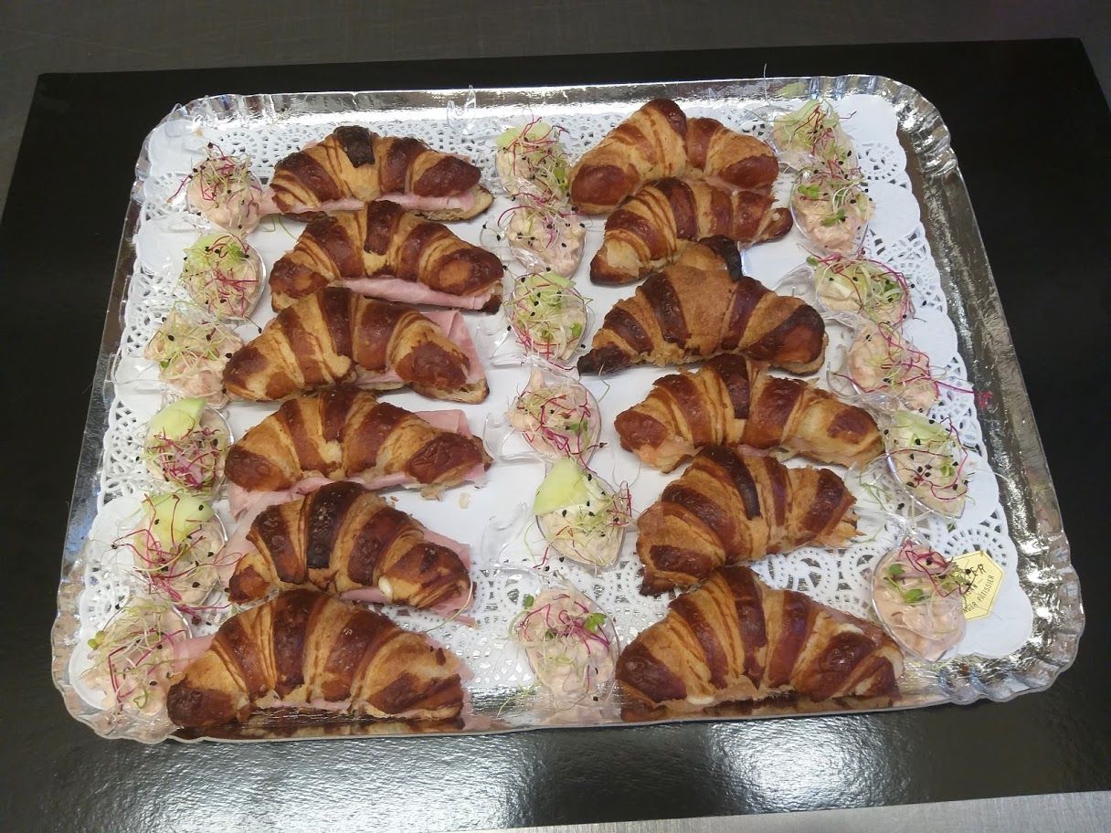 Plateau de croissants et d'amuse-gueules sur un napperon blanc, disposés sur un plateau en argent.