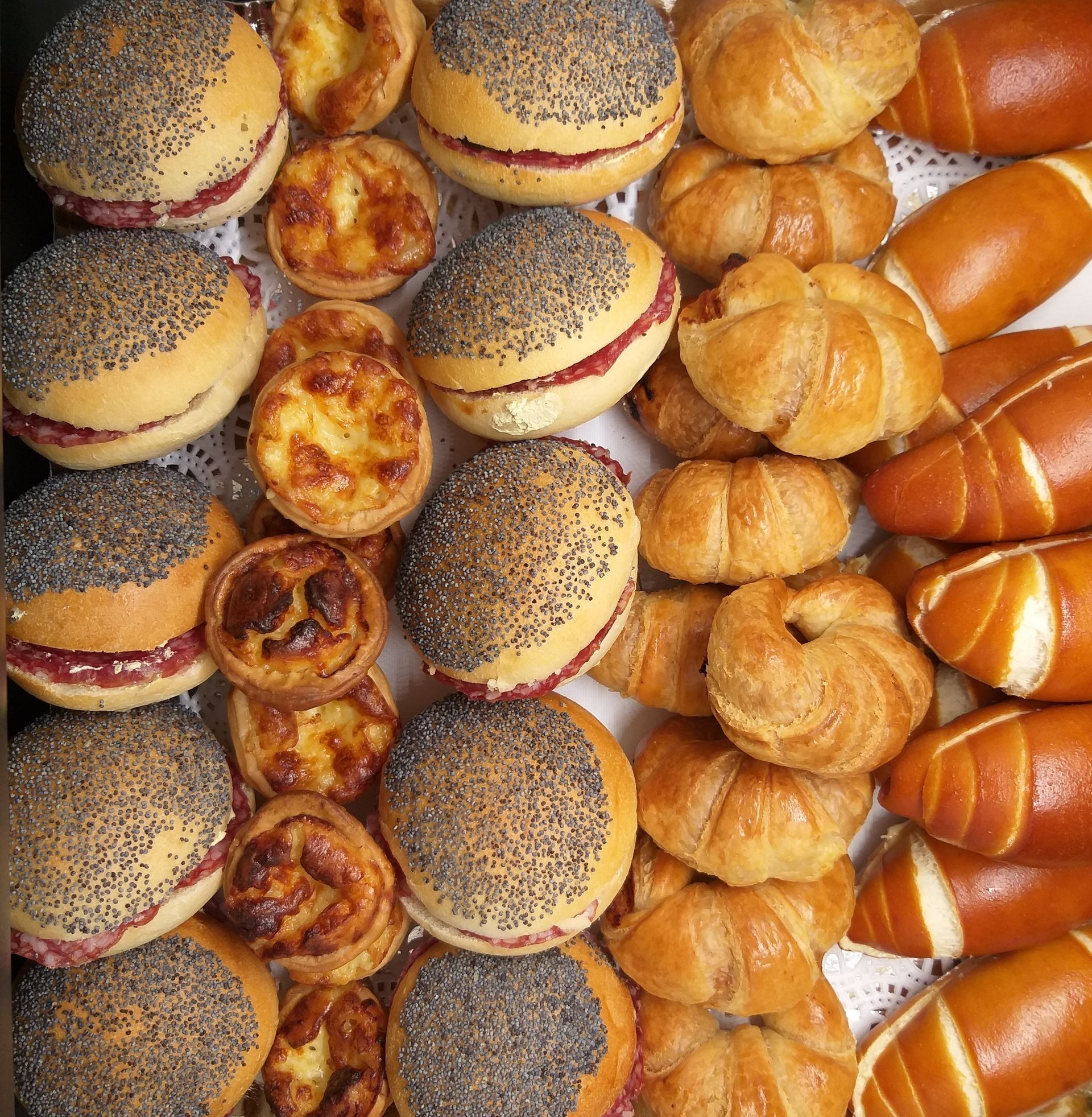 Assortiment de petits pains, pâtisseries et petits pains aux graines de pavot sur un plateau.