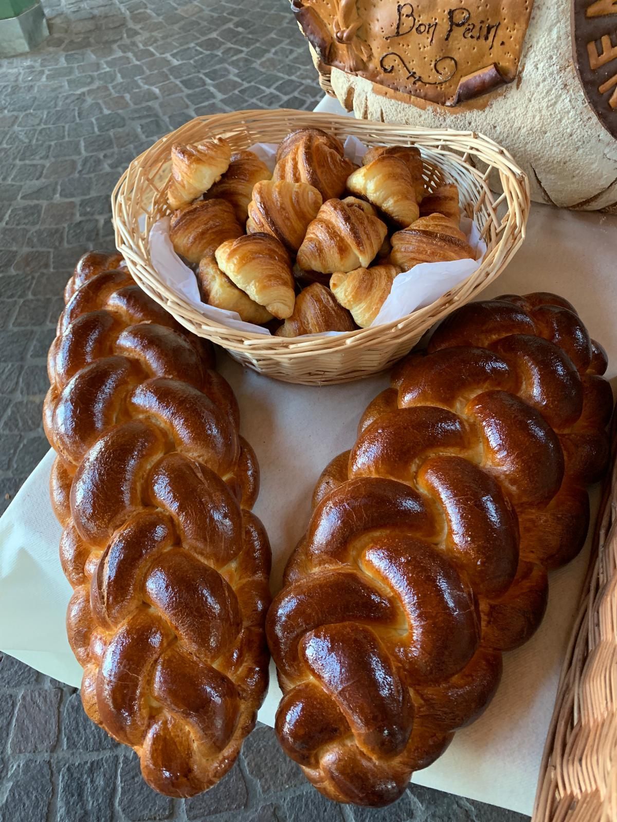 Deux pains tressés avec une corbeille de croissants.