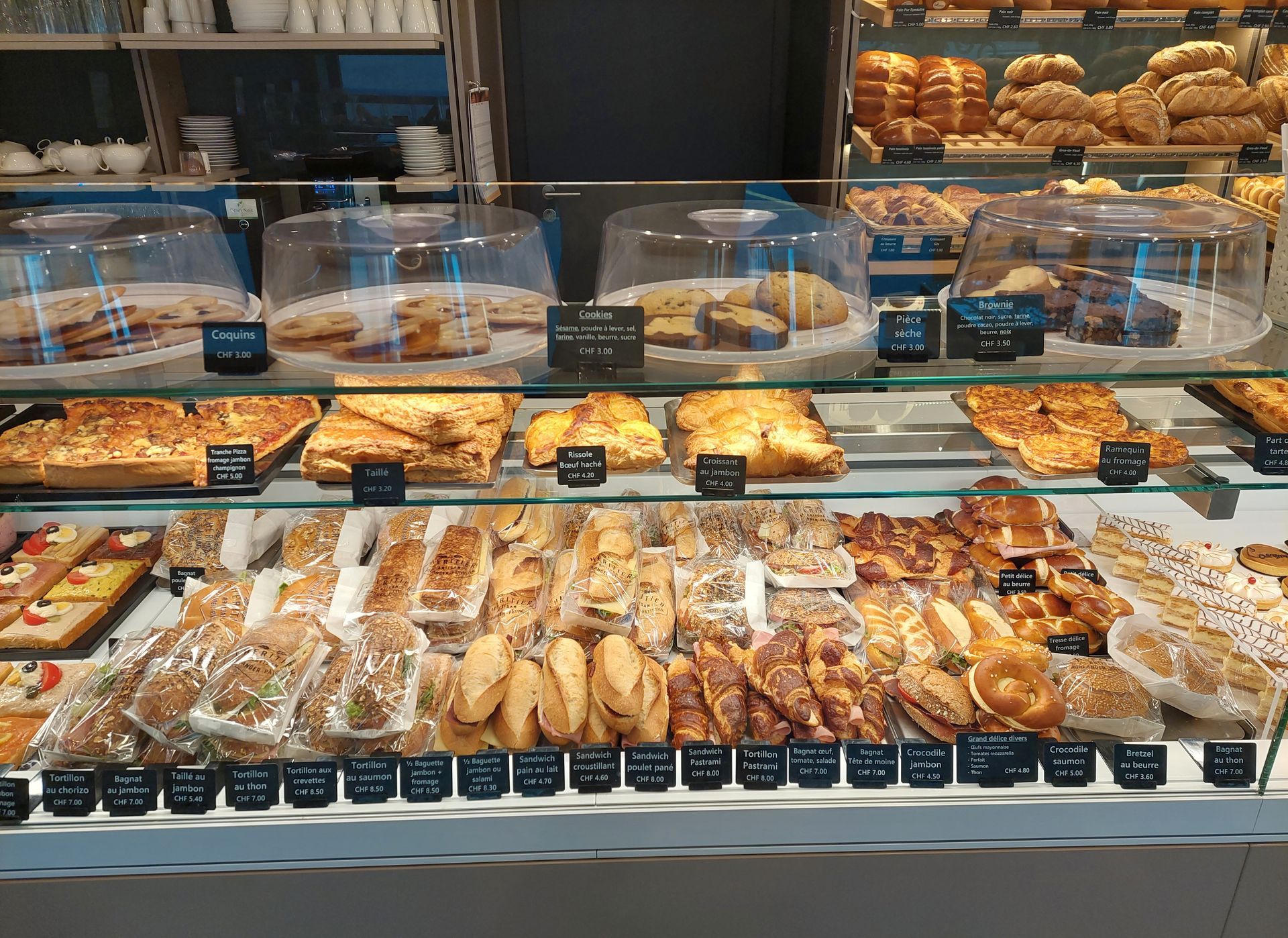 Vitrine de boulangerie remplie de divers produits de boulangerie, notamment du pain, des pâtisseries et des gâteaux.