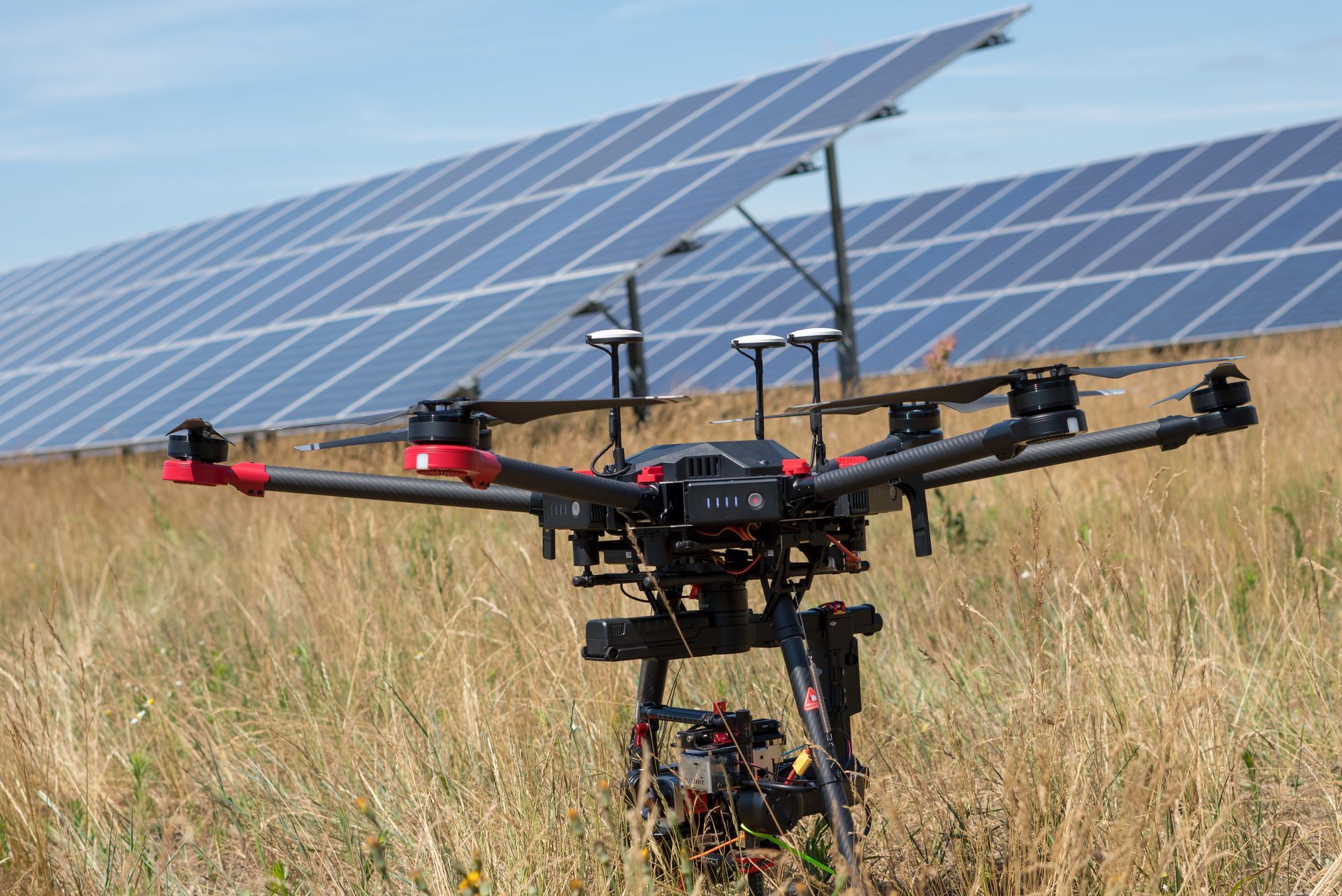 Un drone posé dans un champ devant des panneaux solaires