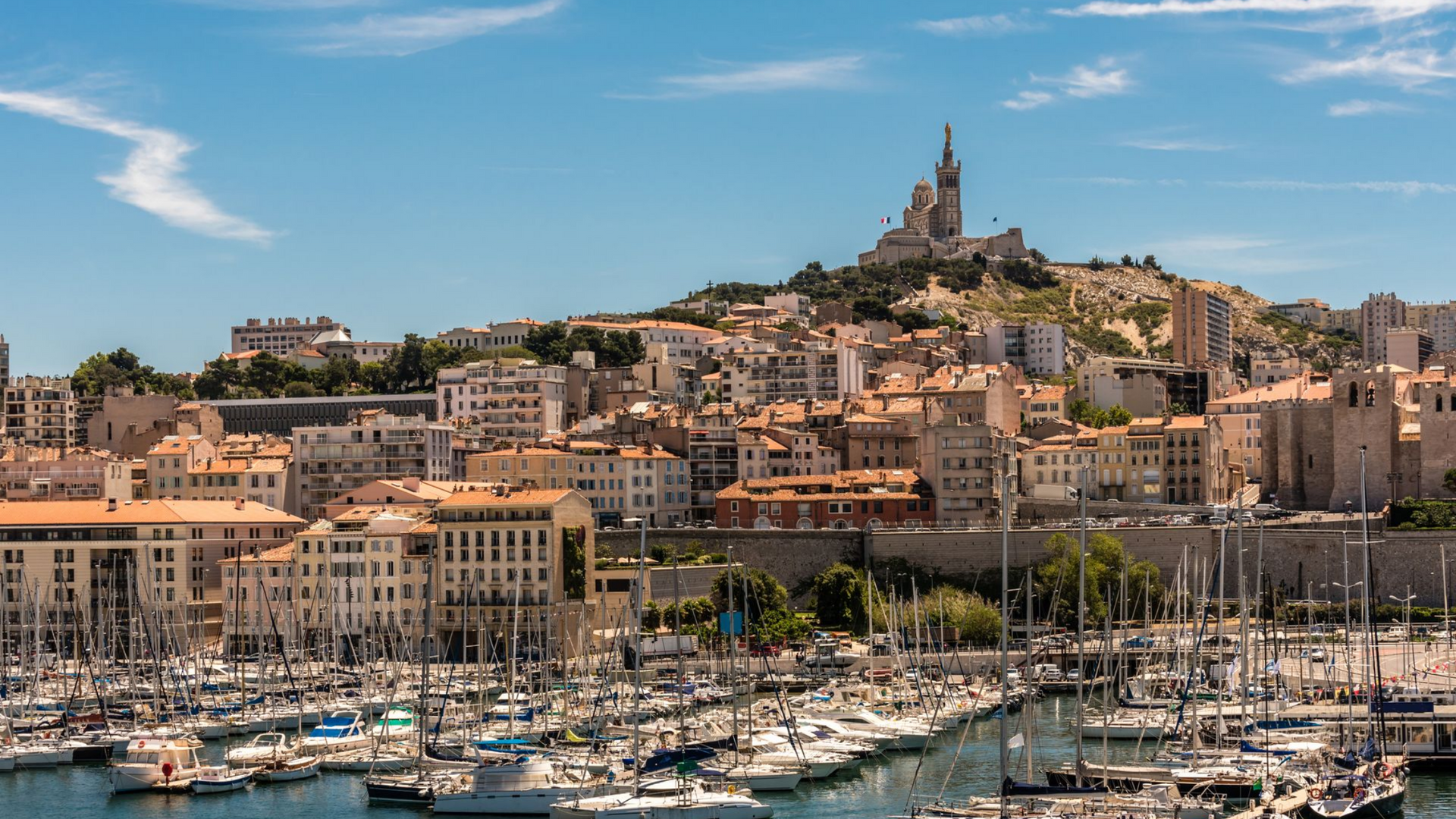 La basilique Notre-Dame de la Garde surplombe le Vieux-Port animé de Marseille, où amarrent de nombreux voiliers.