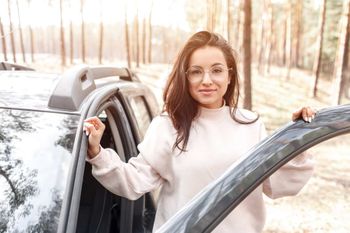 Una mujer sale de un coche en el bosque.