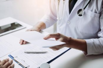 Un médico está hablando con un paciente mientras sostiene un trozo de papel.