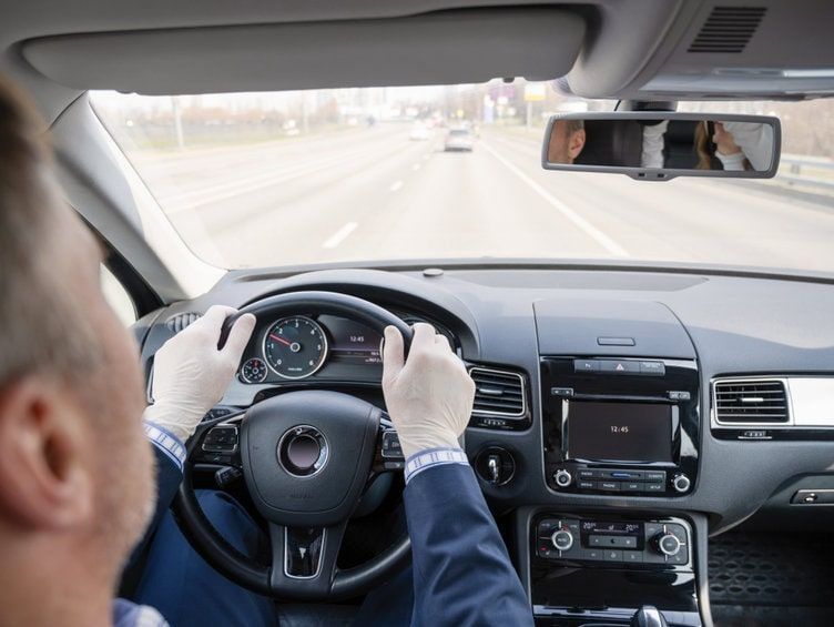 Un hombre con traje conduce un coche por una autopista.