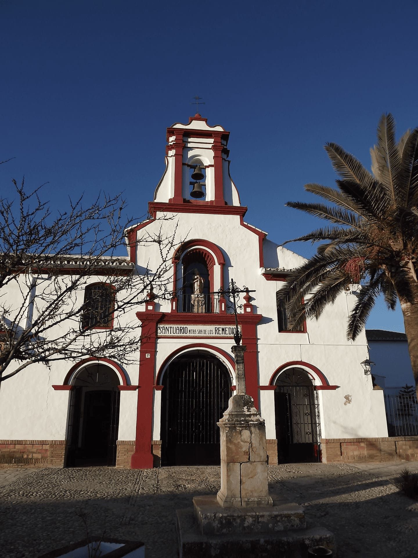 Una iglesia blanca y roja con una palmera delante de ella.