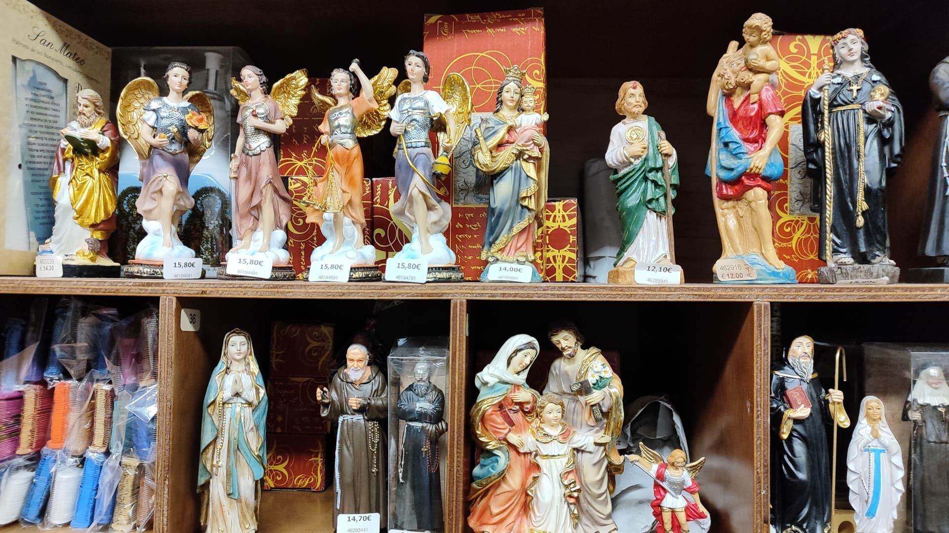 Un estante lleno de muchas estatuas de figuras religiosas.