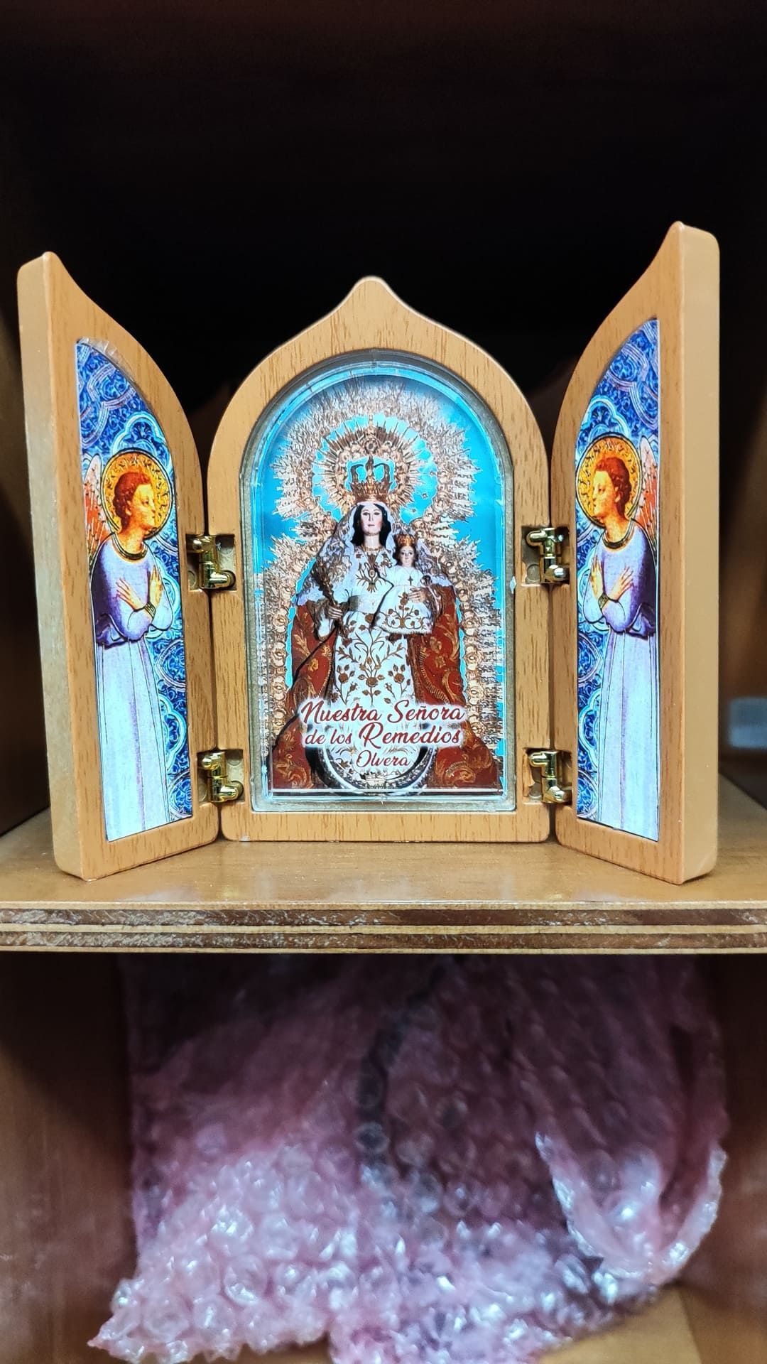 Un icono religioso de madera con ángeles está sobre un estante.