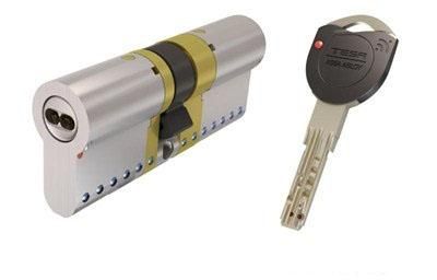 Cerradura de cilindro plateada con llave insertada junto a otra llave a juego sobre un fondo blanco.