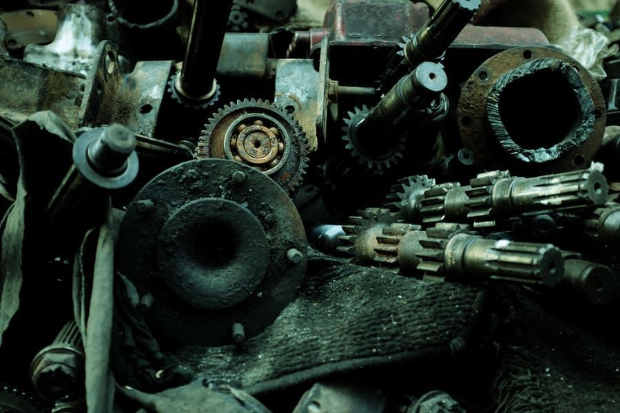 Un montón de piezas de metal oxidadas, incluidos engranajes y ejes.